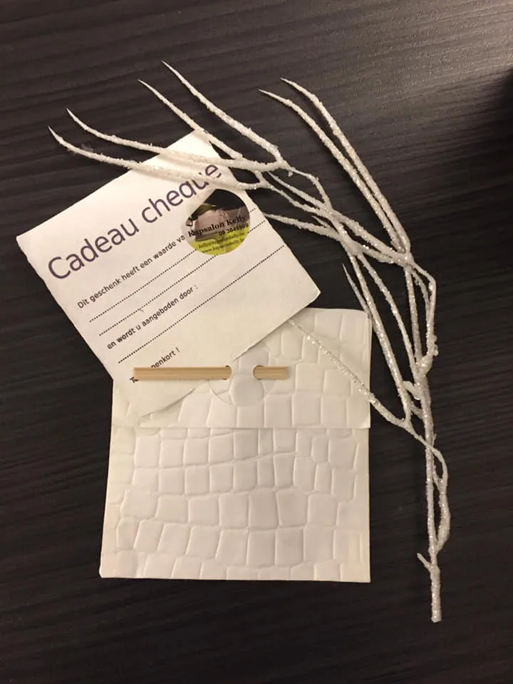 Geschenkbon van Kapsalon Kelly met witte omslag en decoratieve witte tak